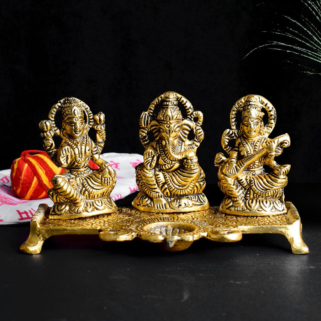 Graceful metal idol featuring Goddess Lakshmi, Goddess Saraswati, and Lord Ganesha with a diya, intricately crafted to symbolize prosperity, knowledge, and blessings. Ideal for worship or as a decorative centerpiece. India’s Largest Pooja Accessories Brand – www.satvikworld.com