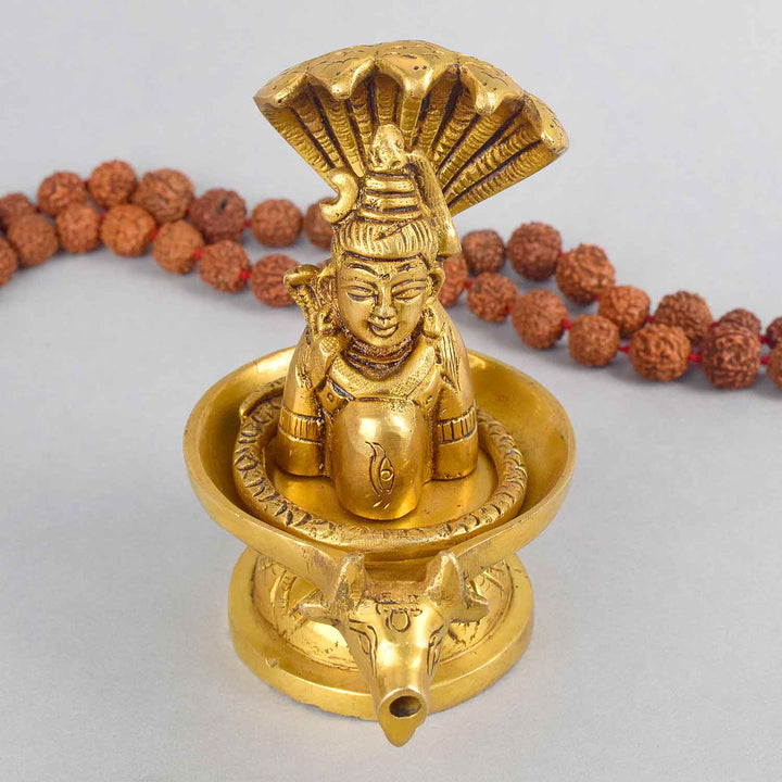 4.7-inch brass Shivalingam and Sheshnag figurine, intricately crafted to represent Lord Shiva's divine energy and protection. The figurine features Sheshnag coiled around the Shivalingam, symbolizing power and spiritual significance. Perfect for pooja rooms, home temples, or as a devotional gift. India’s Largest Pooja Accessories Brand – www.satvikworld.com