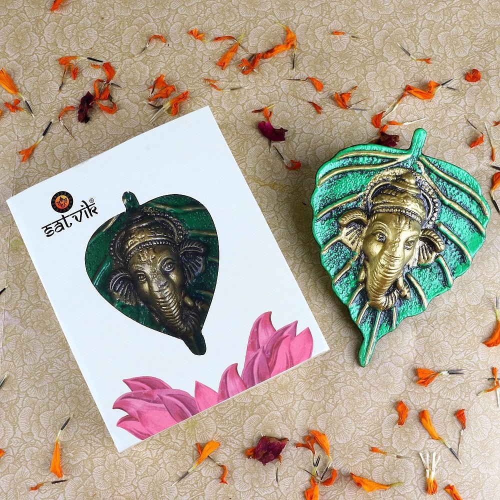 Green-colored 1 Pc Lord Ganesh Face intricately carved on a leaf patta wall hanging for traditional and spiritual home décor. India’s Largest Pooja Accessories Brand – www.satvikworld.com


