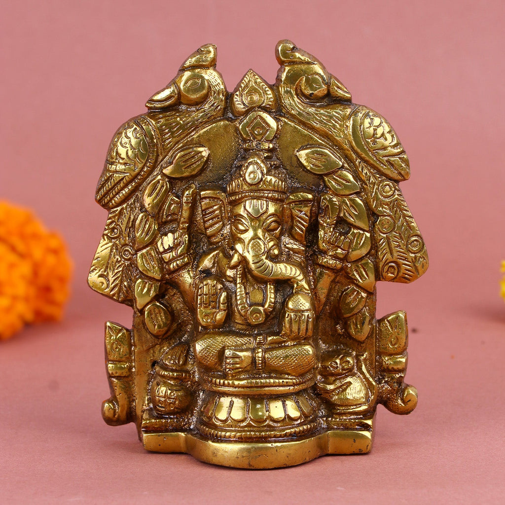 Brass Lord Ganesha idol seated in a traditional pose, adorned with intricate carvings and surrounded by peacock and floral motifs. India’s Largest Pooja Accessories Brand – www.satvikworld.com