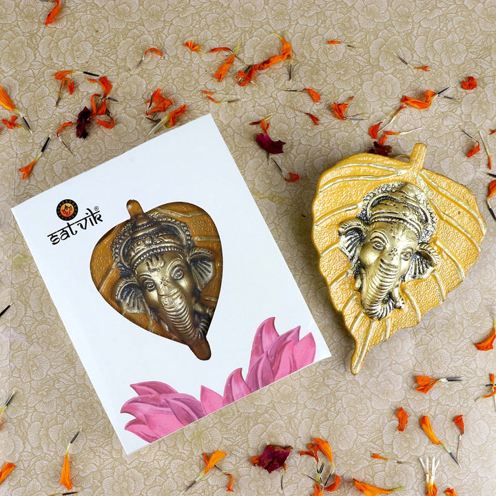 Yellow-colored 1 Pc Lord Ganesh Face crafted on a leaf patta wall hanging for traditional and spiritual home décor. India’s Largest Pooja Accessories Brand – www.satvikworld.com